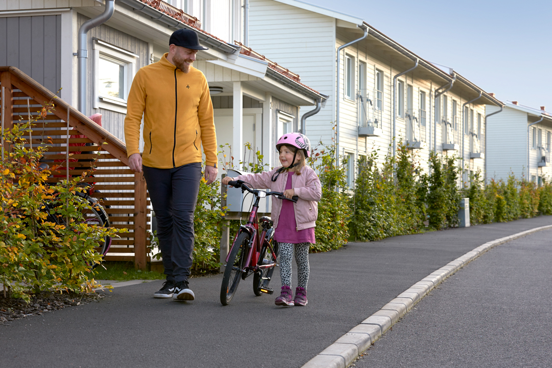 Flicka leder sin cykel på promenad med sin pappa